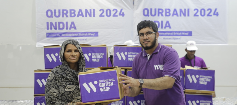 How to make a charitable waqf a volunteer hands a Qurbani 2024 food package to a woman in India as part of a humanitarian aid effort by International British Waqf.